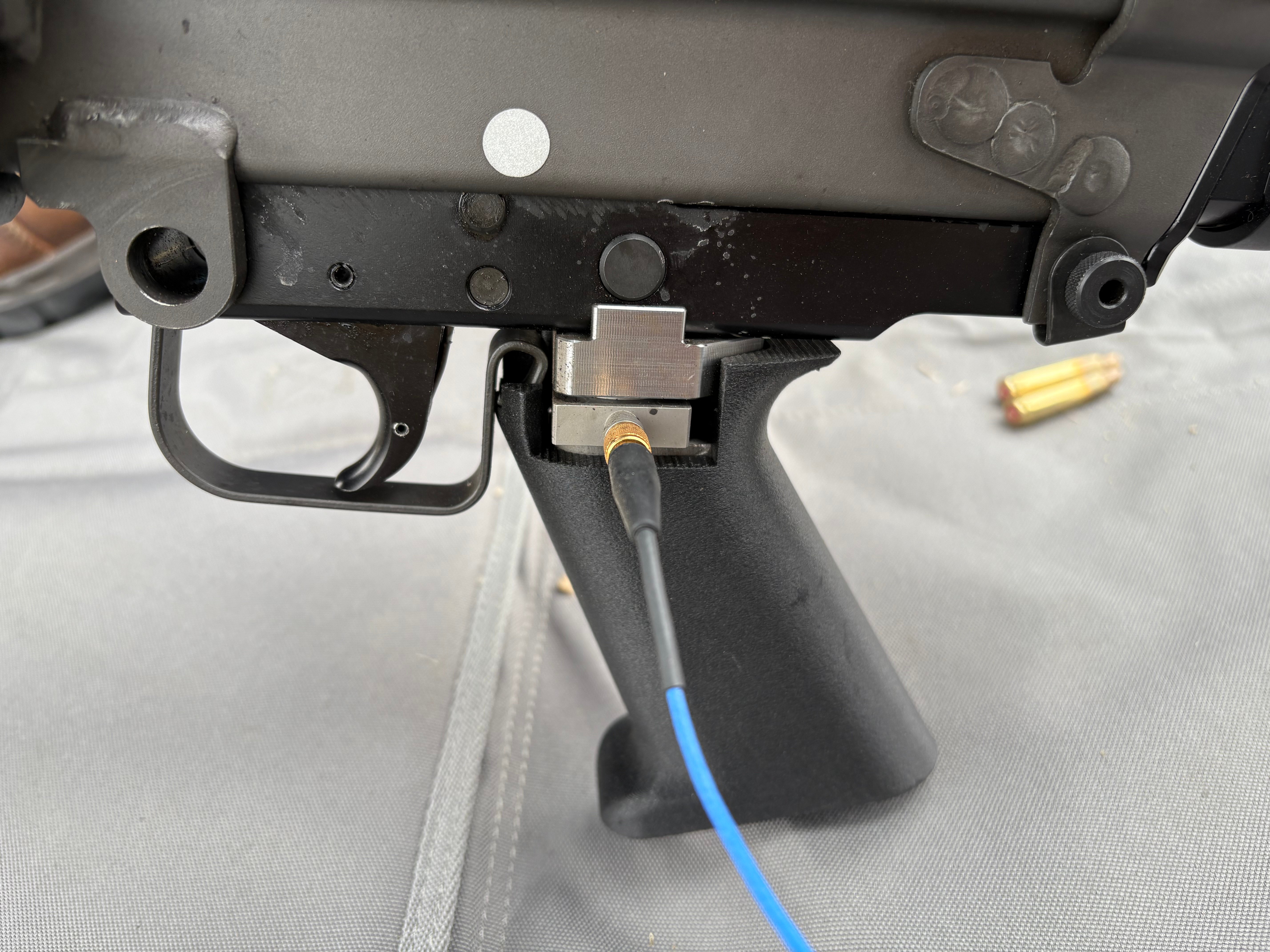 Instrumented firearm pistol grip with triaxial IEPE/ICP force sensor to measure forces transferred to pistol grip during shooting.